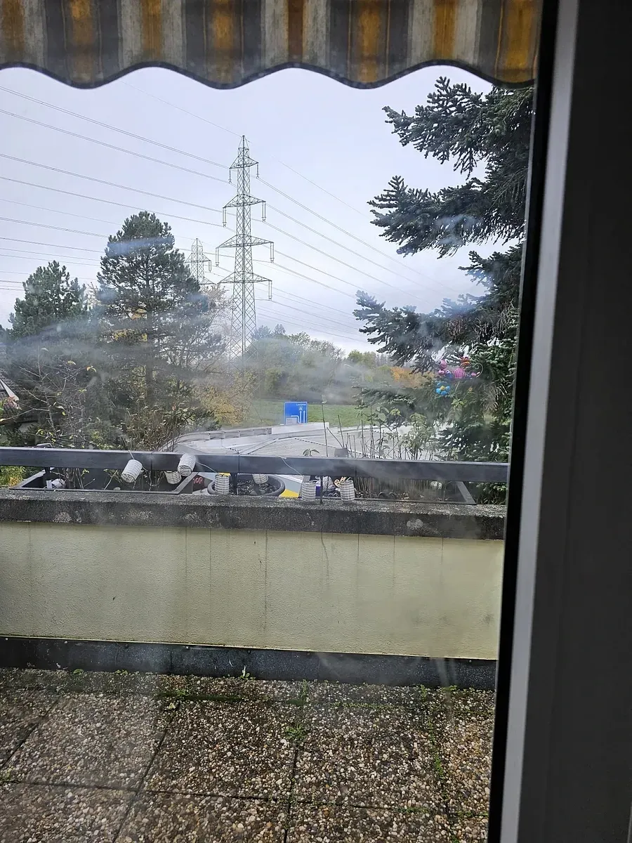 Une vue d'un balcon depuis une fenêtre avec un auvent rayé