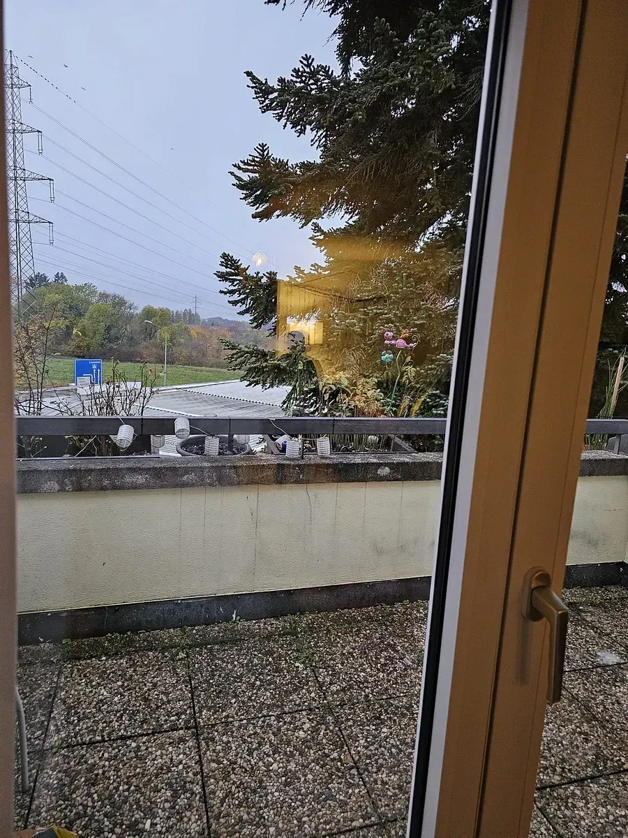 Une fenêtre avec vue sur un balcon et des arbres
