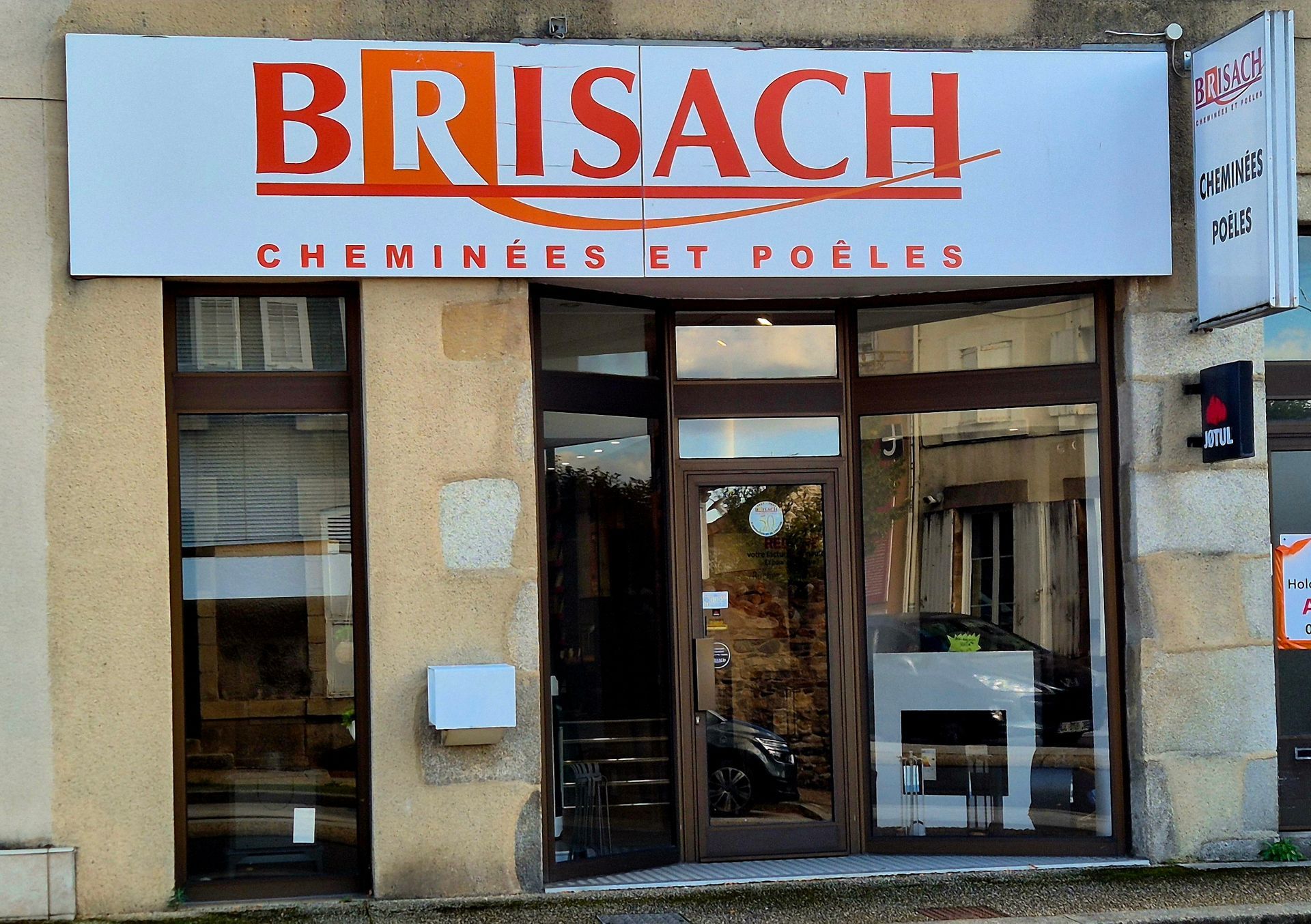 Devanture de BRISACH avec une enseigne rouge et blanche sur un bâtiment en pierre.