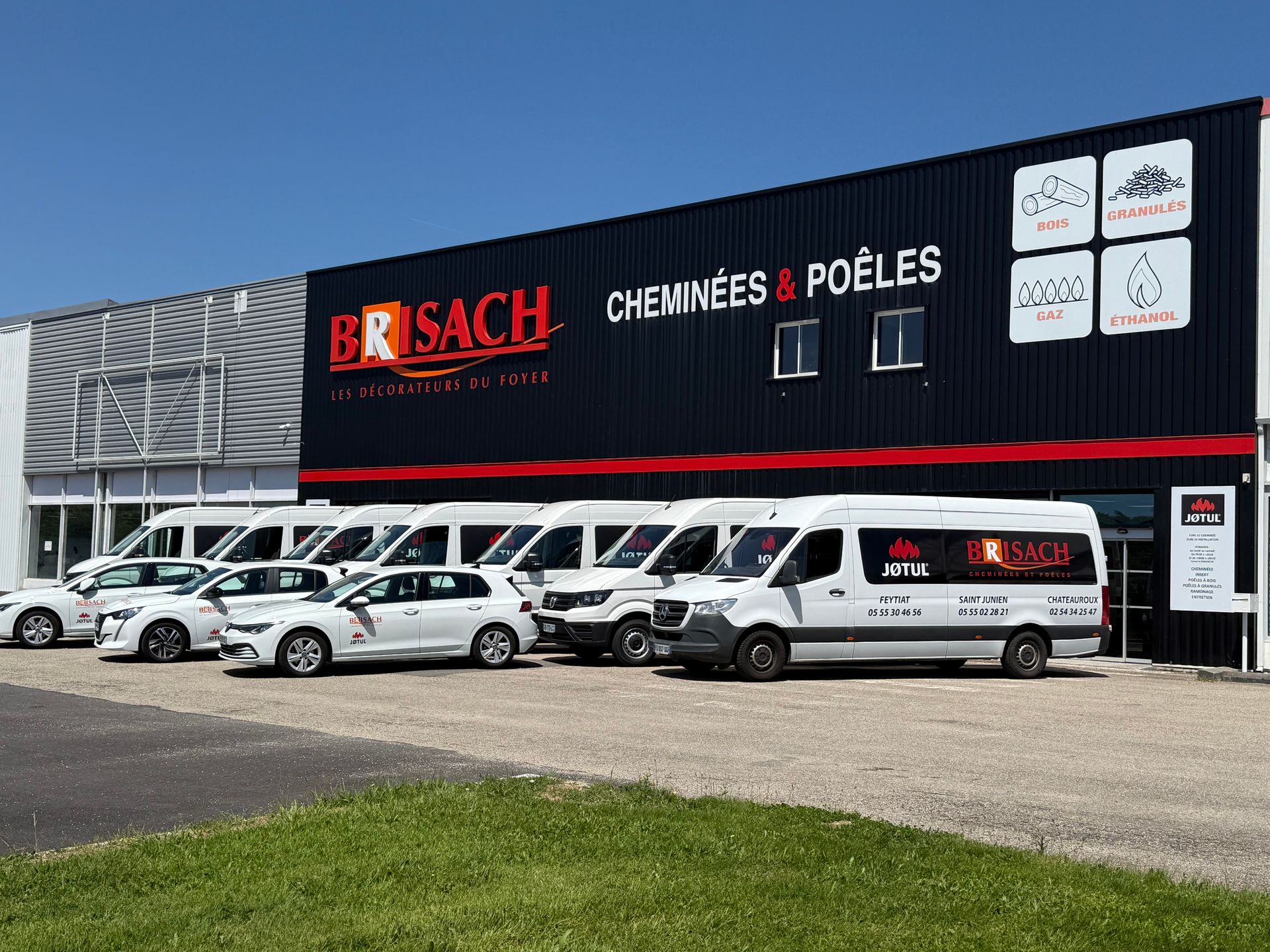 Façade du showroom de cheminées et de poêles BRISACH, avec les véhicules de l'entreprise garés devant.