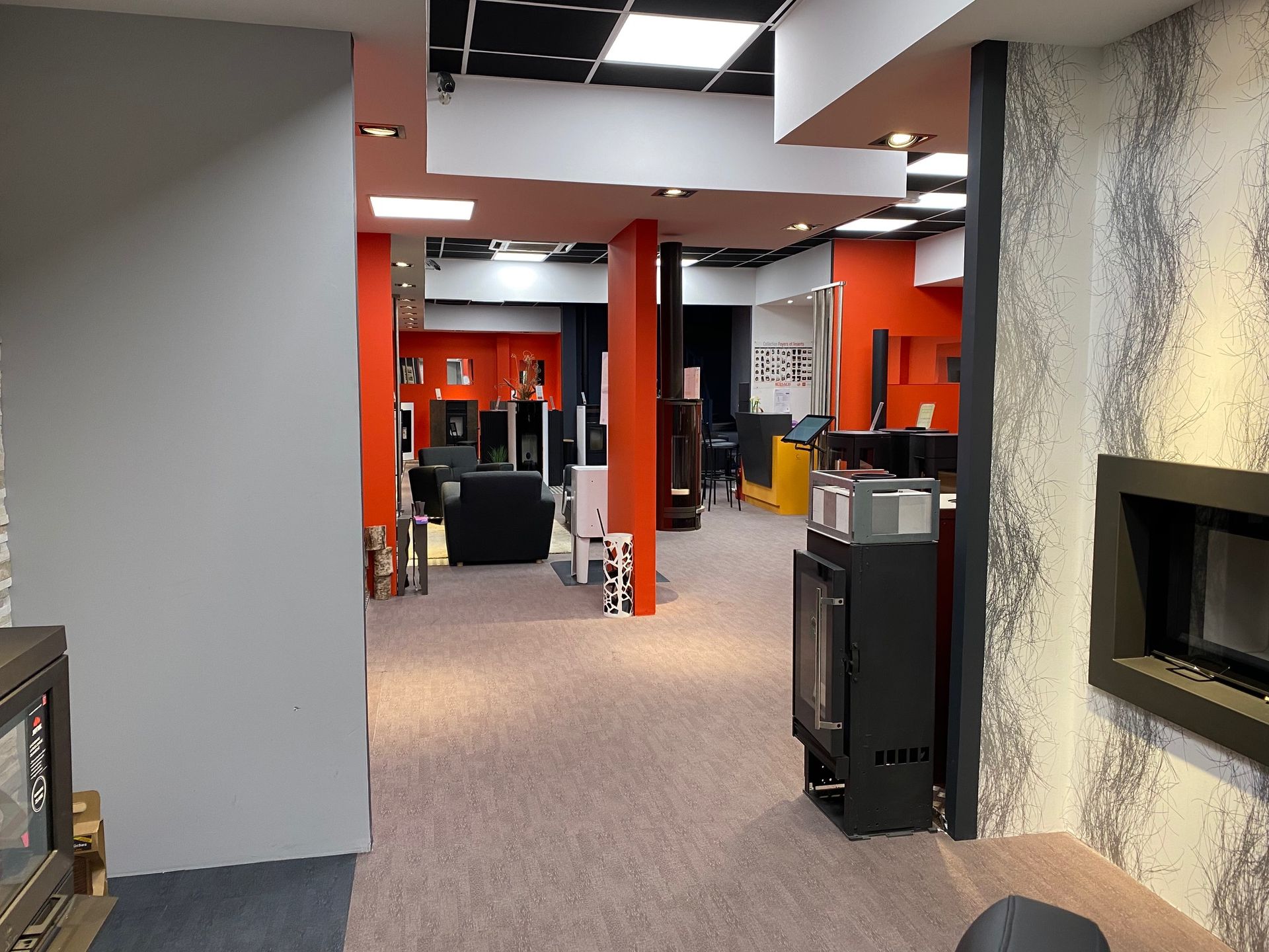 Intérieur d'un magasin de poêles et cheminées aux murs rouges.