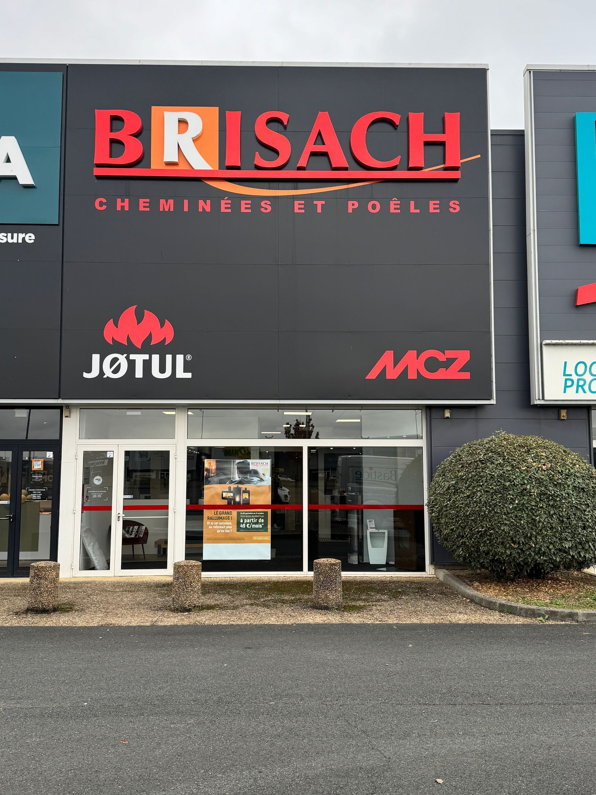 Façade d’un magasin BRISACH avec une enseigne rouge et les logos JOTUL et MCZ sur un bâtiment commercial gris.