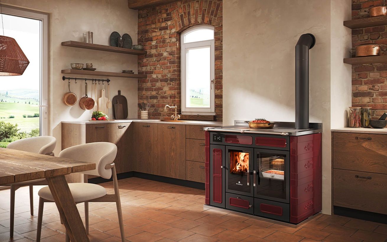 Cuisine rustique avec des placards en bois, des murs en briques et une cuisinière à bois rouge où brûle un feu.
