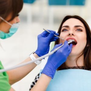 Una mujer se está haciendo examinar los dientes por un dentista.