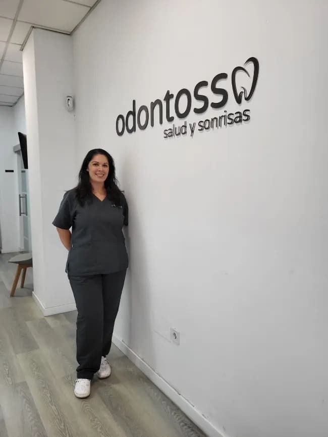 Una mujer está parada frente a una pared que dice odontoss