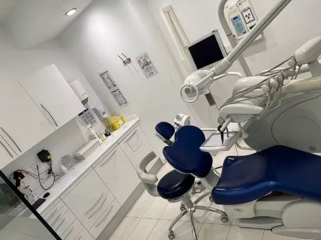 Un consultorio dental con una silla azul y gabinetes blancos.