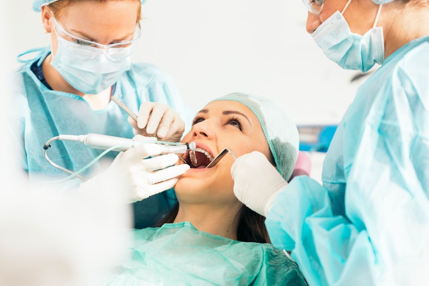 Una mujer está siendo examinada por dos dentistas.