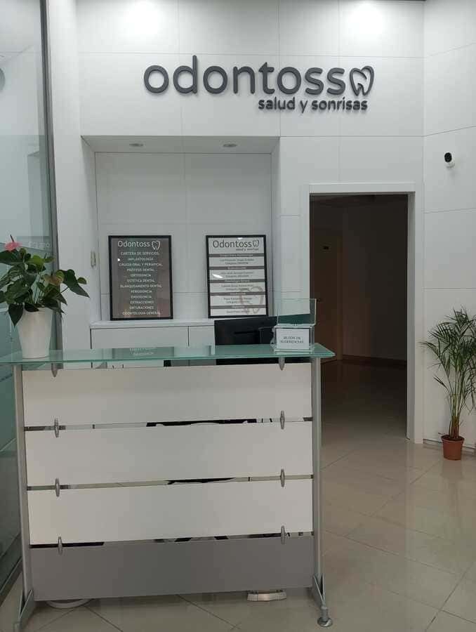 Un consultorio dental con un mostrador de recepción y un cartel en la pared.