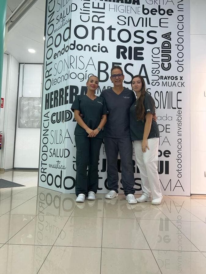 Un grupo de personas paradas frente a una pared con palabras en español.