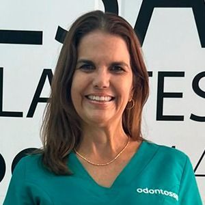 Una mujer con una blusa verde sonríe delante de un cartel.