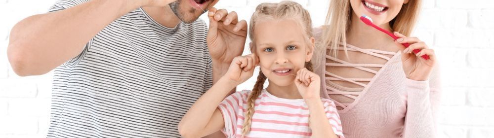 Una familia se cepilla los dientes juntos y sonríe.