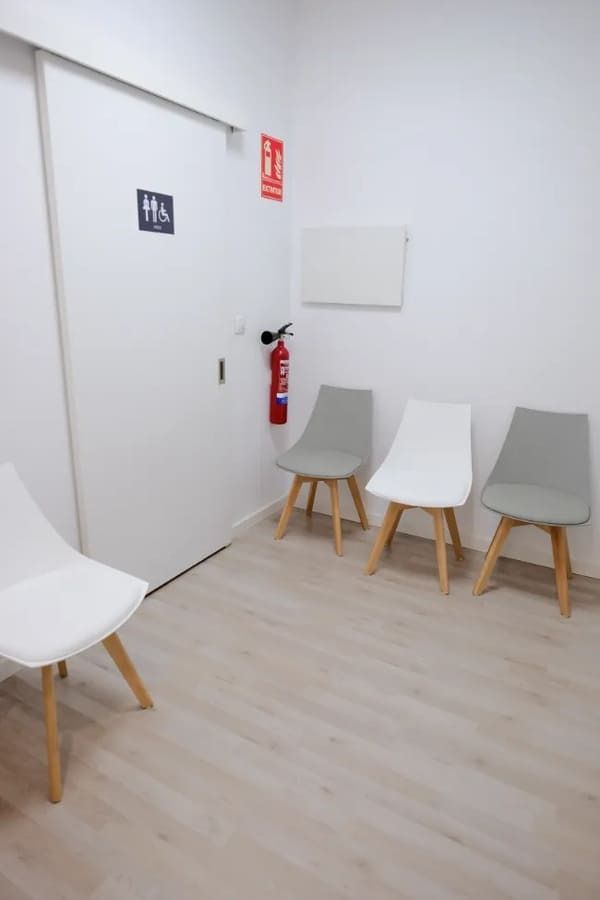 Una sala de espera con sillas y un extintor en la pared.