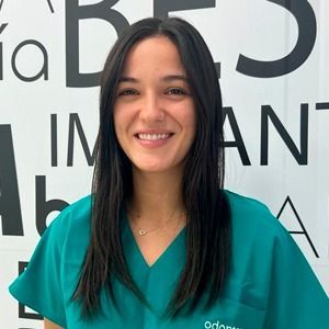 Una mujer con una blusa verde sonríe delante de un cartel.