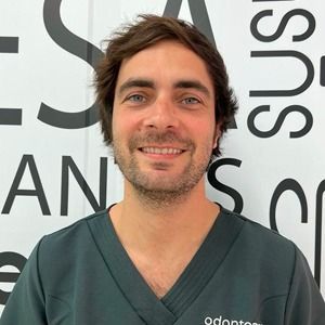 Un hombre con barba viste una blusa negra y sonríe.