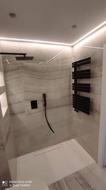 Un baño con ducha a ras de suelo y toallero.