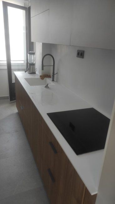 Una cocina con fregadero, horno y ventana.