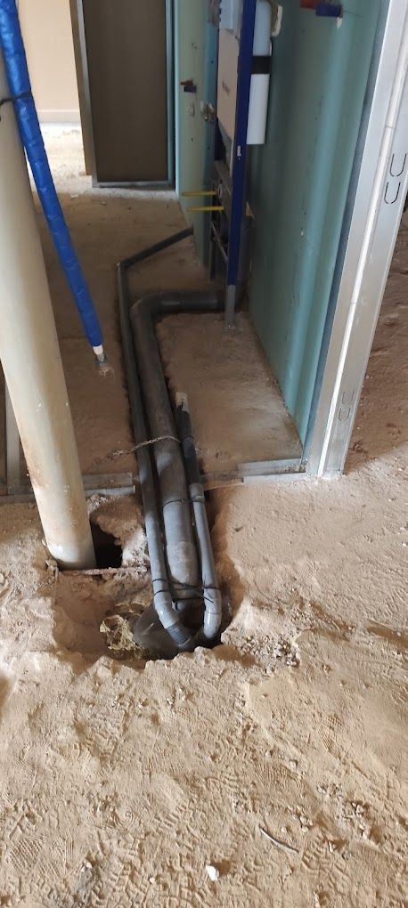 Un agujero en el suelo por el que salen tuberías.