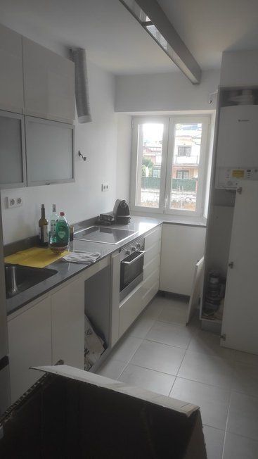 Una cocina con gabinetes blancos, una estufa, un fregadero y una ventana.