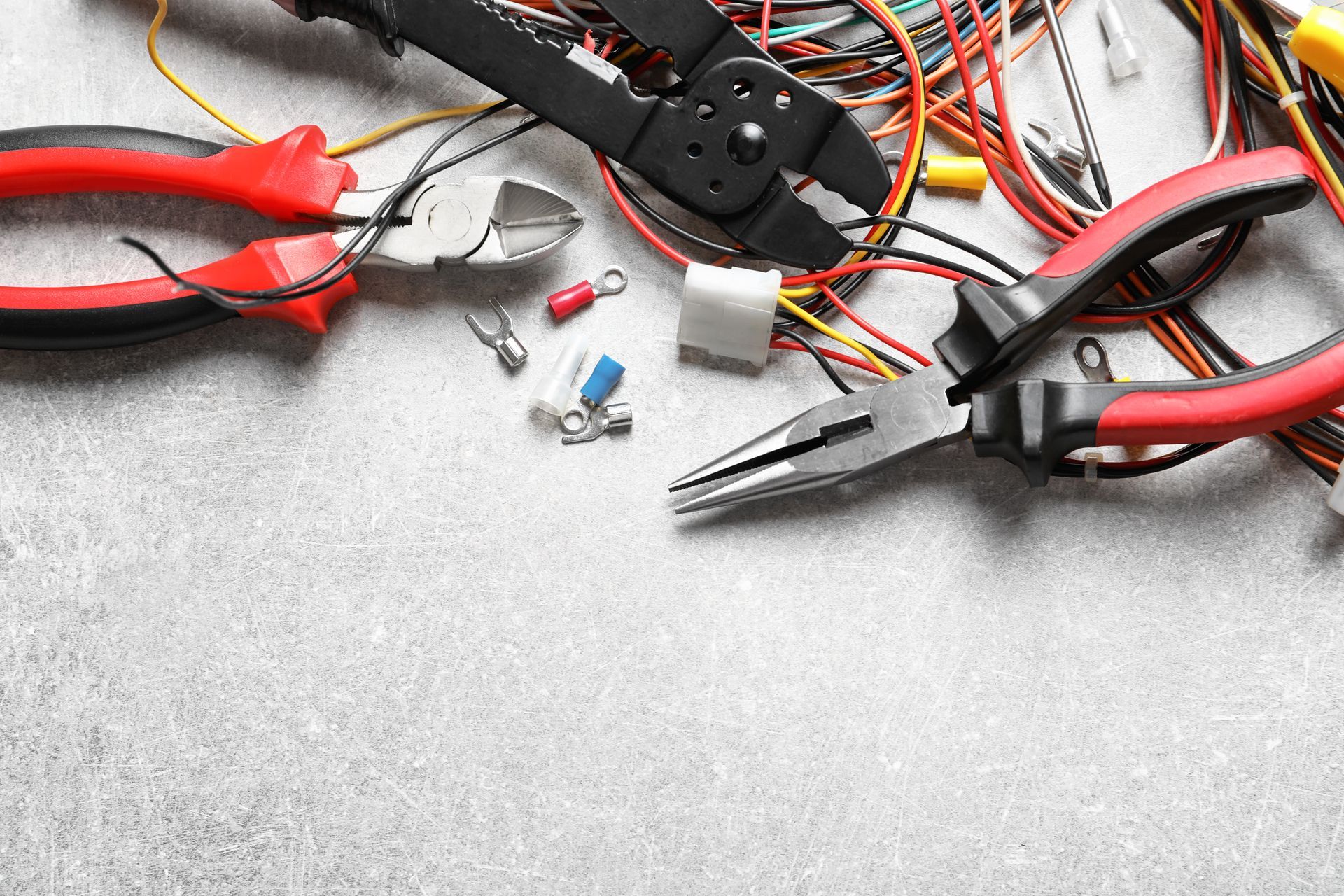 Handwerkzeuge und kleine elektronische Bauteile auf einer grauen Werkbank
