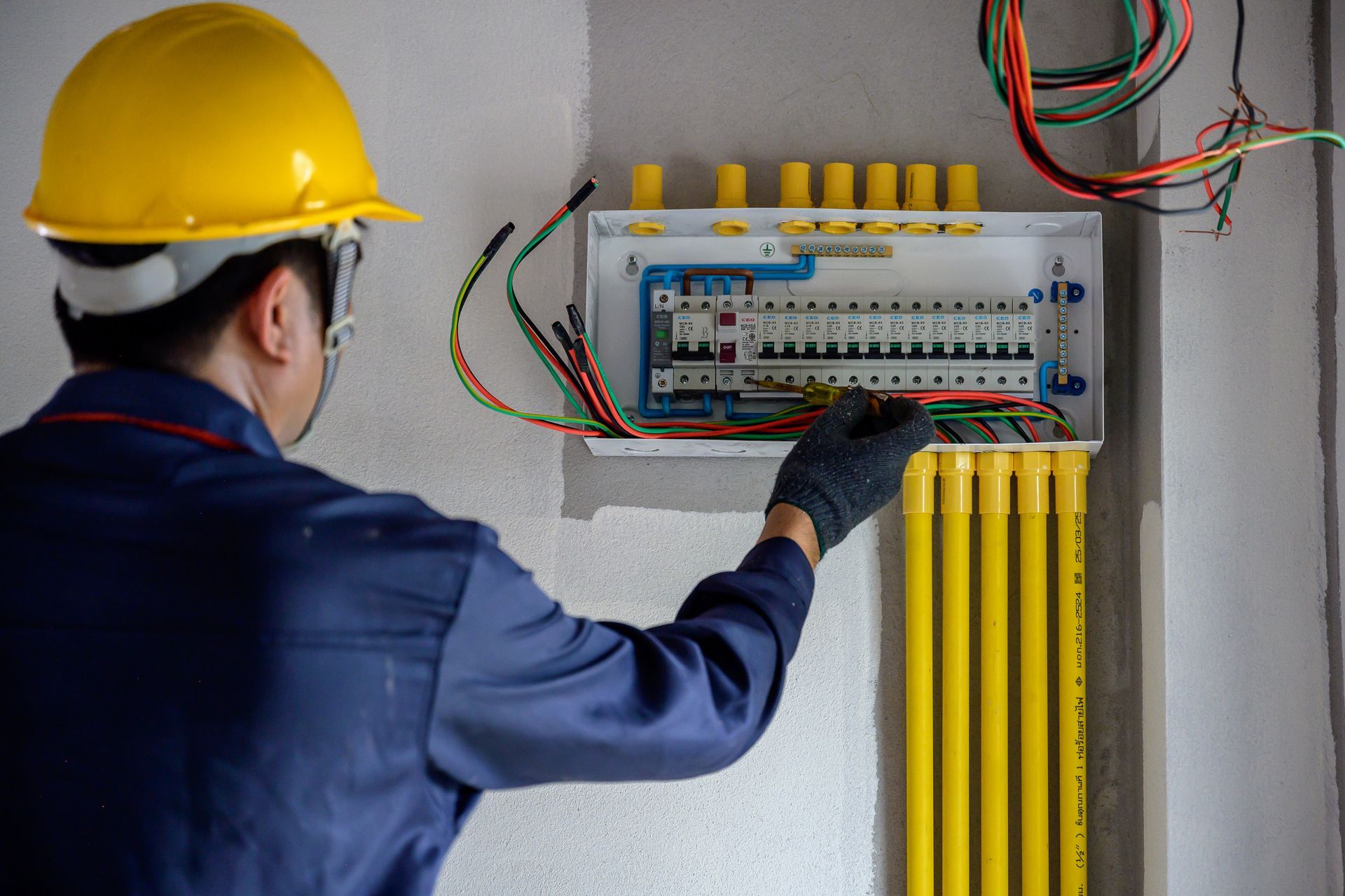 Ein Elektriker verdrahtet einen Sicherungskasten mit Werkzeugen auf einer kleinen Werkbank in der Nähe.