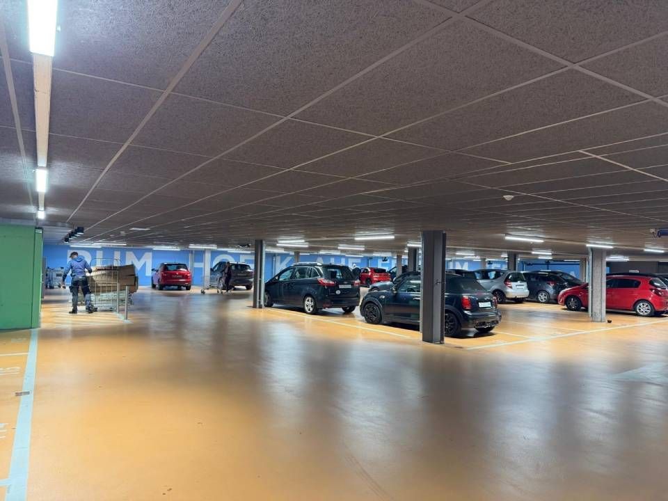 Tiefgarage mit mehreren geparkten Autos und poliertem Betonboden unter schwach beleuchteten Deckenleuchten