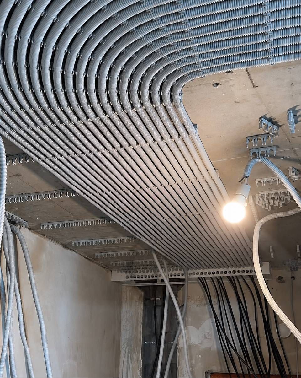 Die Decke befindet sich im Bau und weist freiliegende Leitungen, Kabelkanäle und eine eingeschaltete Arbeitsleuchte auf.