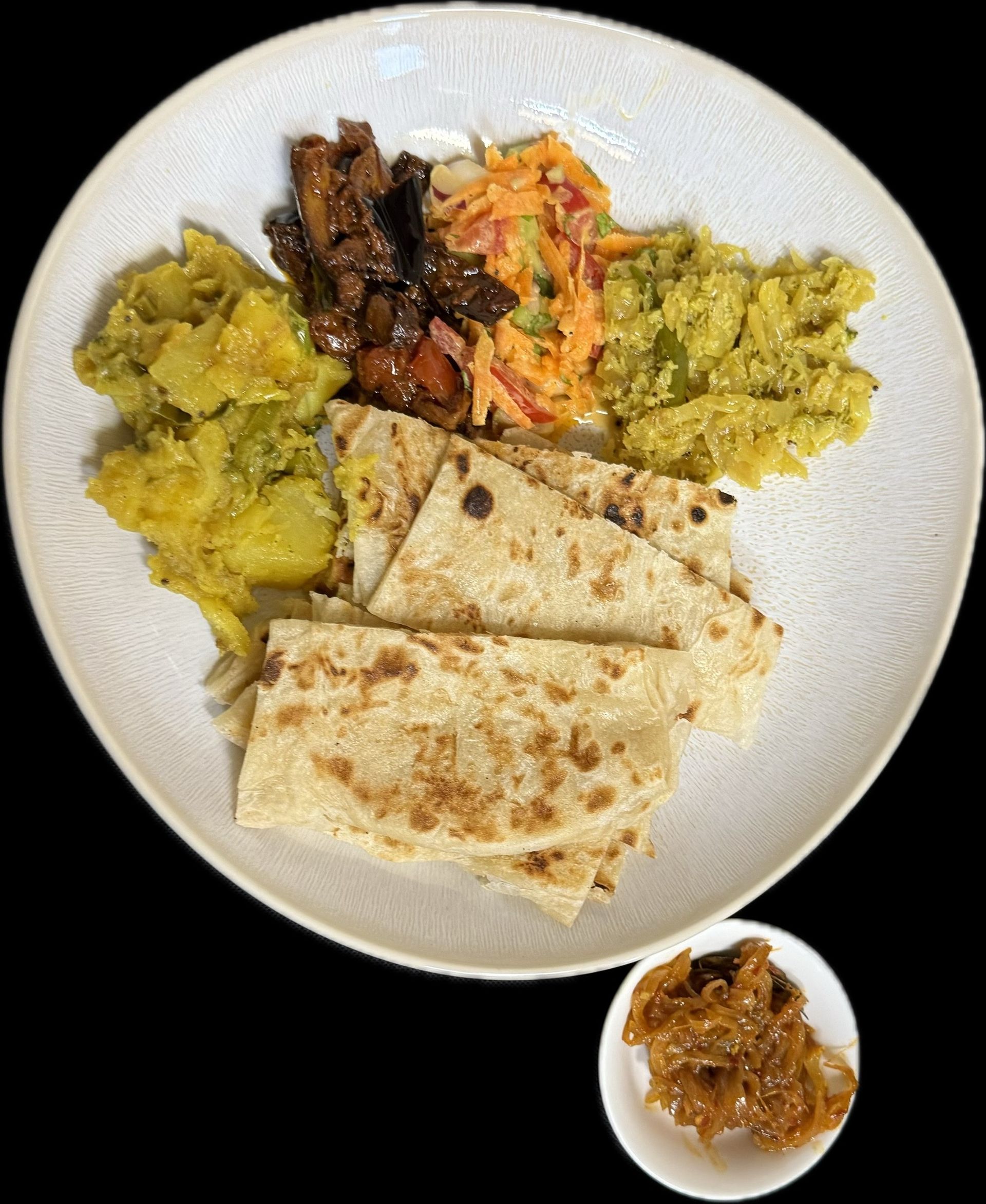 Teller mit sri-lankischem Essen auf einem Tisch, darunter Reis, Curry und Roti.