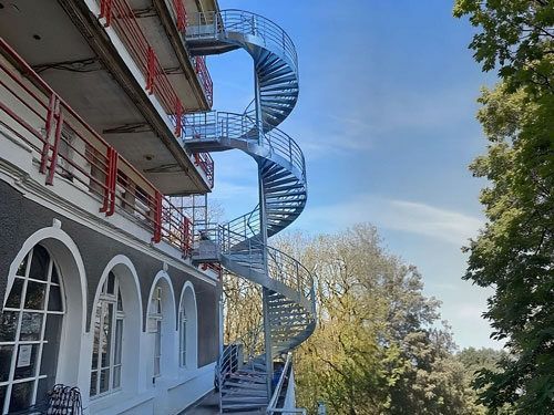 Escalier en colimaçon bleu à côté d'un bâtiment blanc.