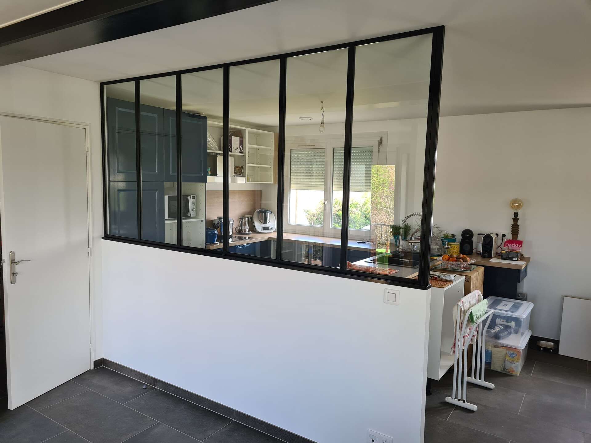 Pièce intérieure avec cloison vitrée à cadre noir et murs blancs.