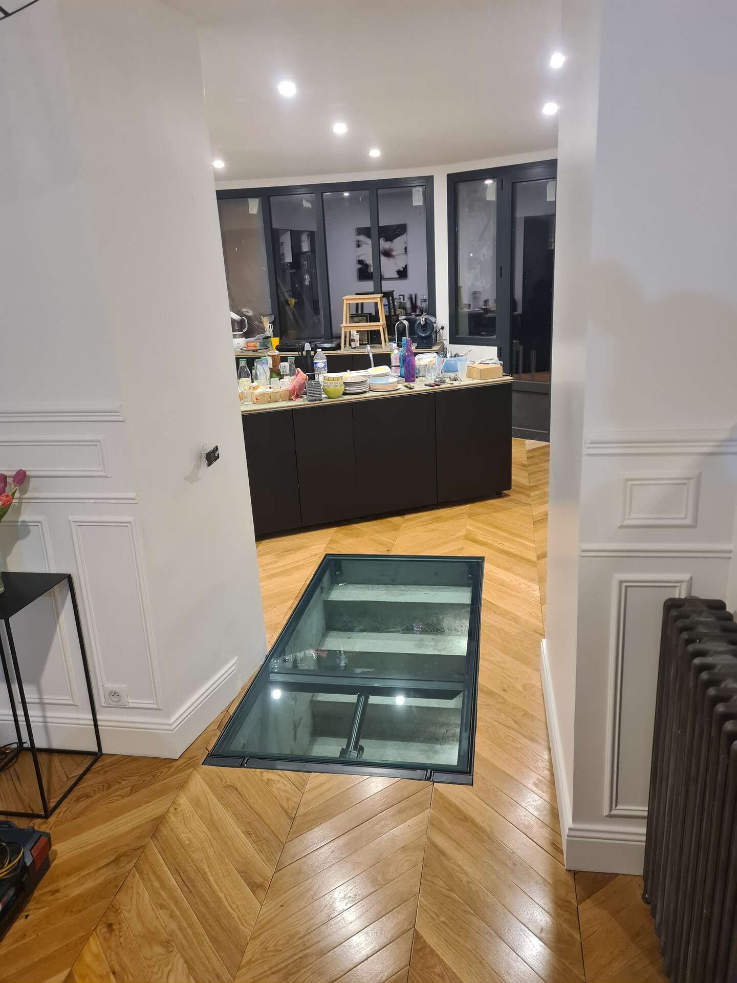 Couloir intérieur avec un panneau de sol en verre menant à un comptoir de cuisine 