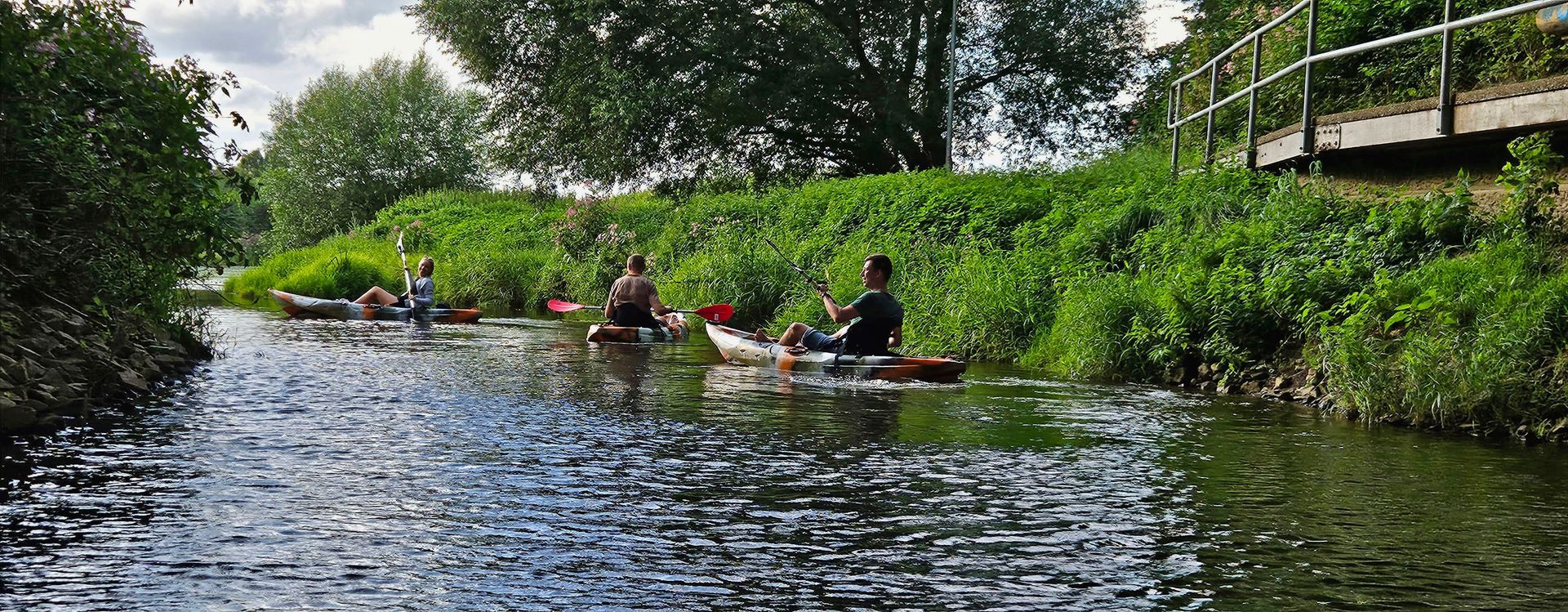 Eine Gruppe von Leuten rudert in Kajaks einen Fluss hinunter.