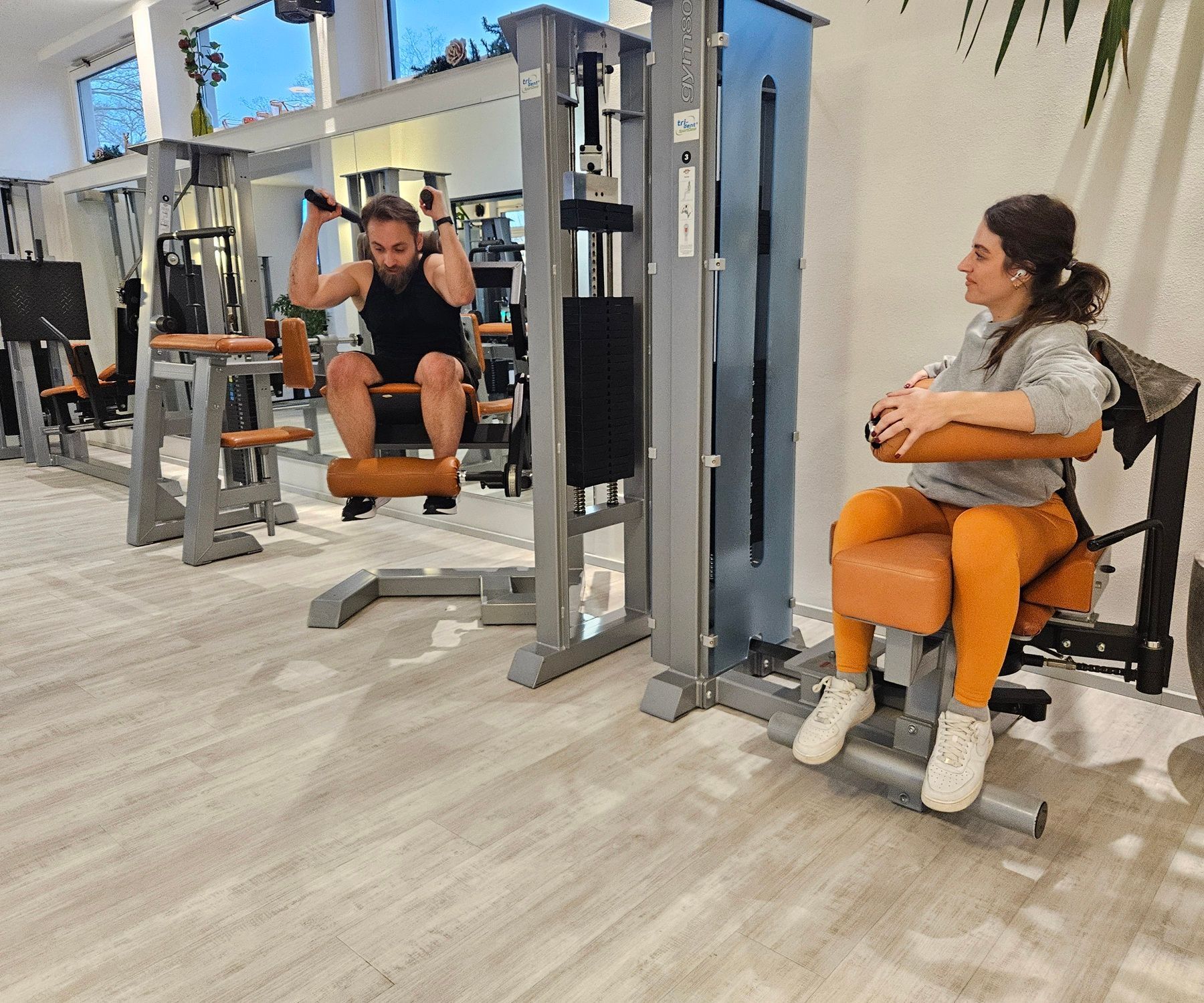 Ein Mann und eine Frau benutzen Trainingsgeräte in einem Fitnessstudio.