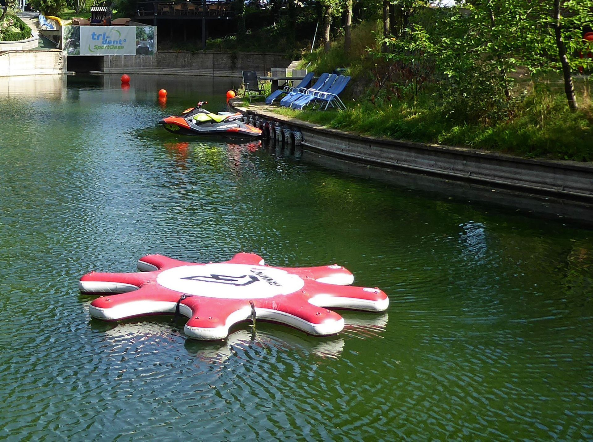 Ein rot-weißer Schwimmkörper in Form einer Sonne schwimmt in einem See