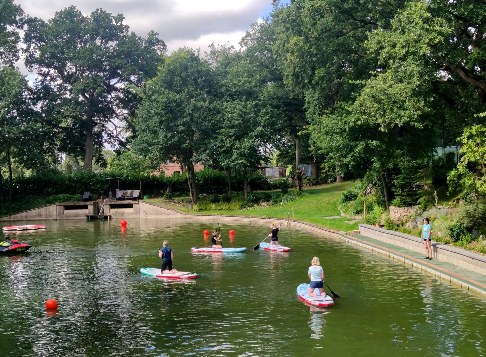 Eine Gruppe von Menschen fährt mit Paddle-Boards auf einem See.