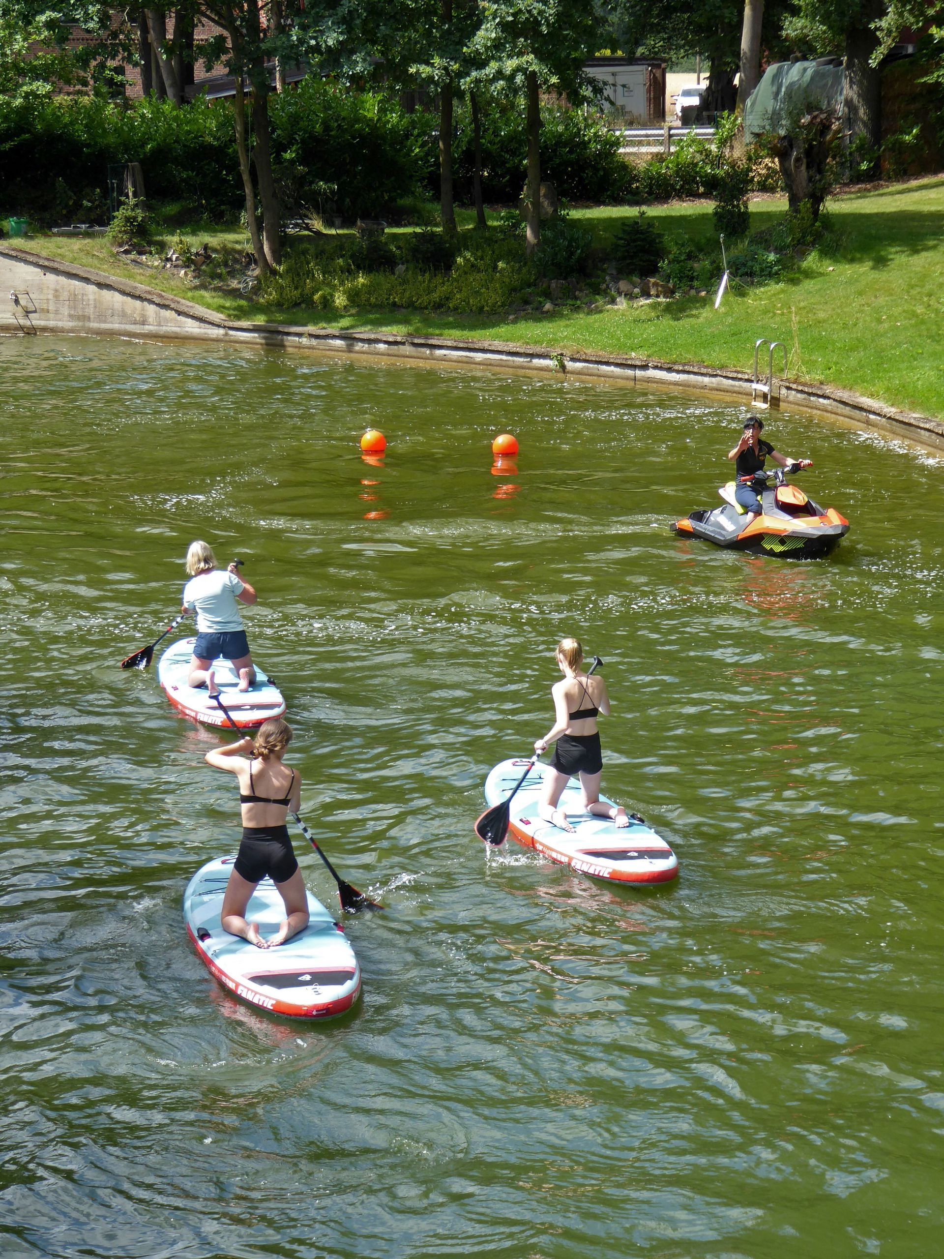 Eine Gruppe von Menschen fährt mit Paddle-Boards auf einem See.