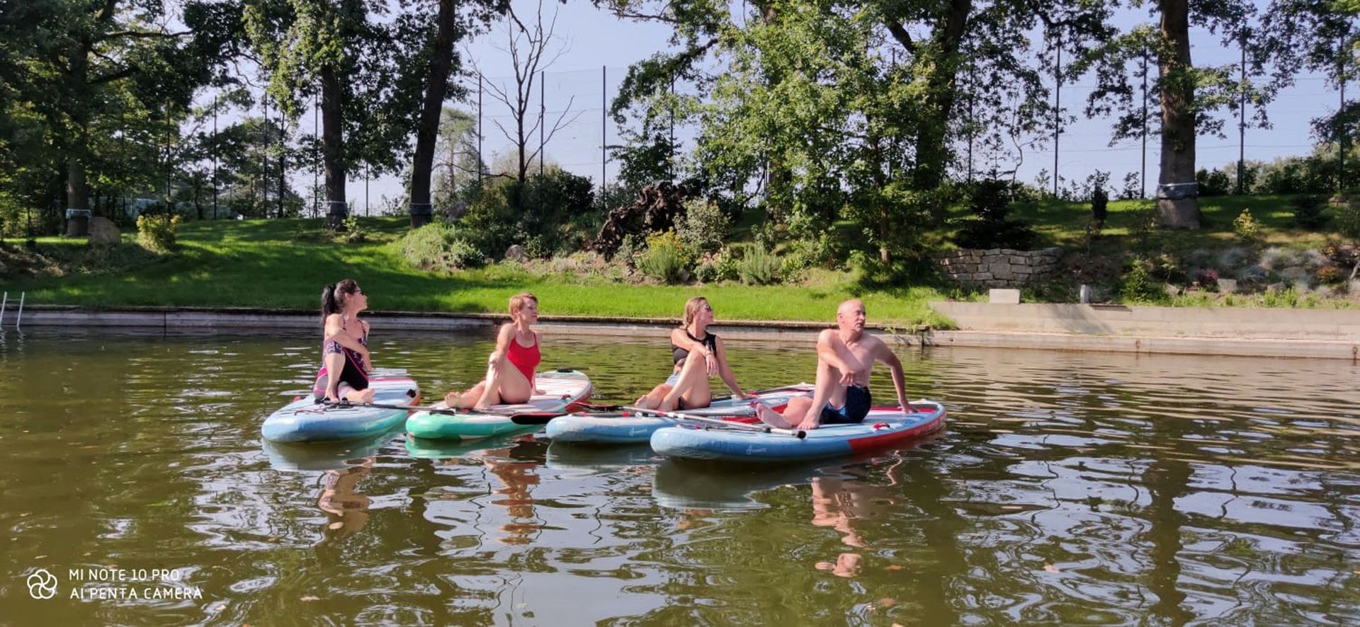 Eine Gruppe von Menschen sitzt auf Paddelbrettern im Wasser.