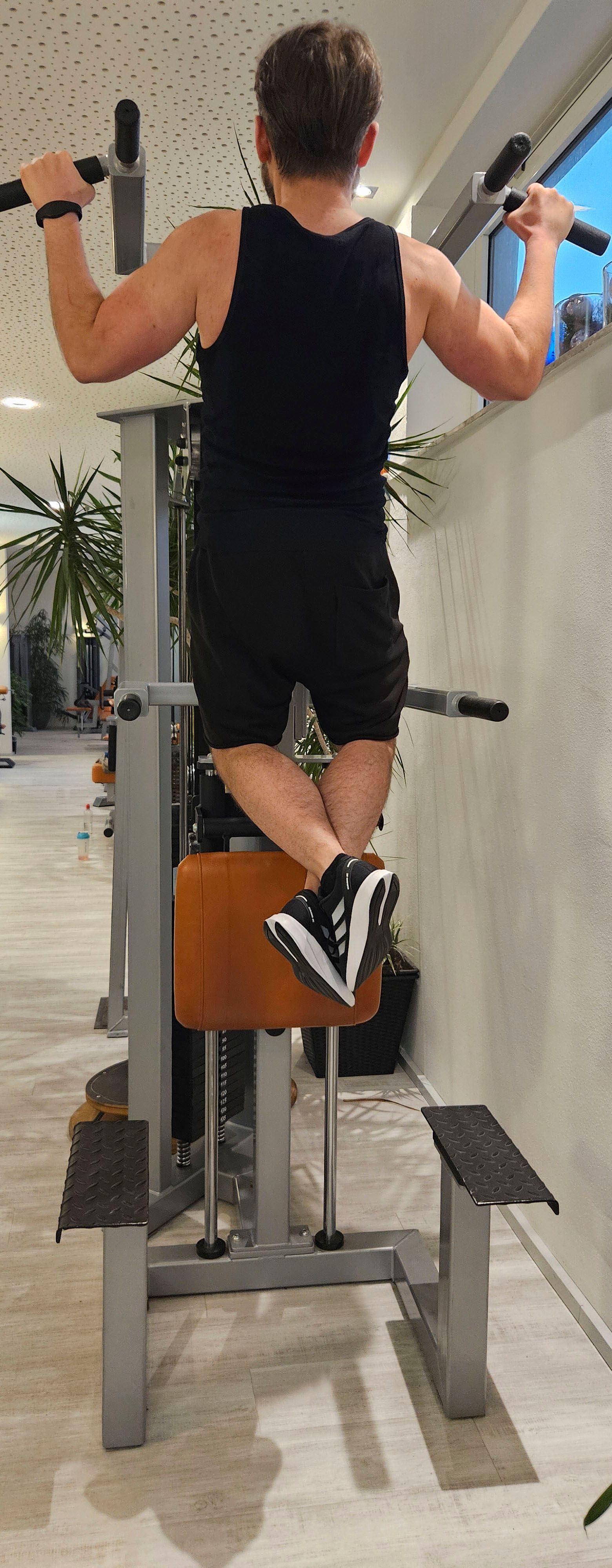 Ein Mann macht in einem Fitnessstudio Klimmzüge an einem Gerät.