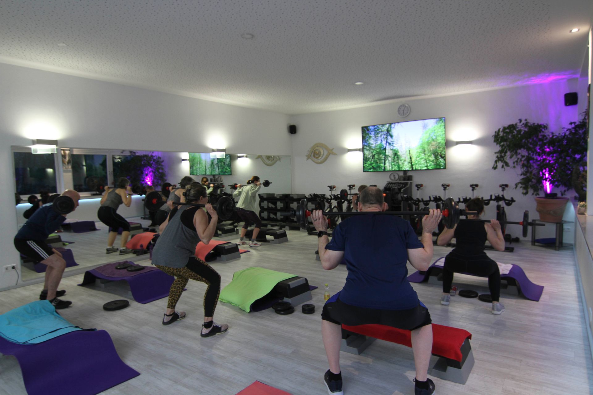 Eine Gruppe von Leuten macht in einem Fitnessstudio Kniebeugen.