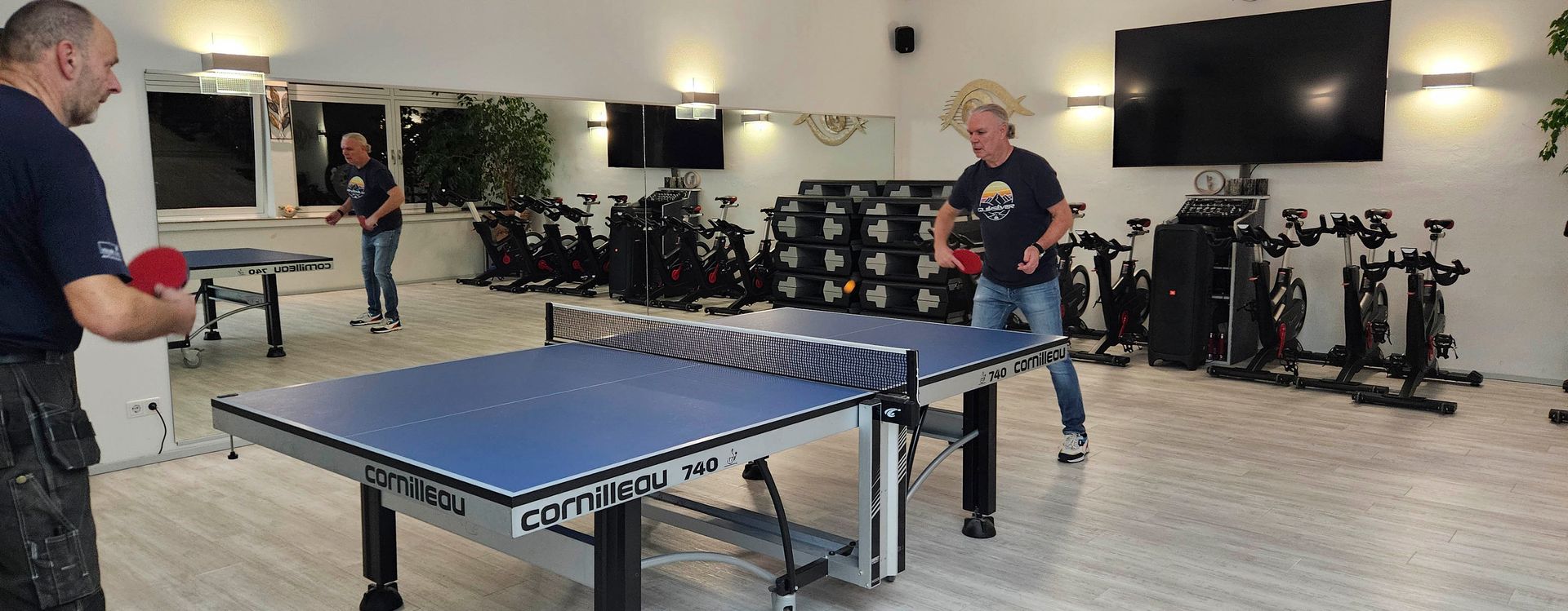 Zwei Männer spielen in einer Turnhalle Tischtennis.