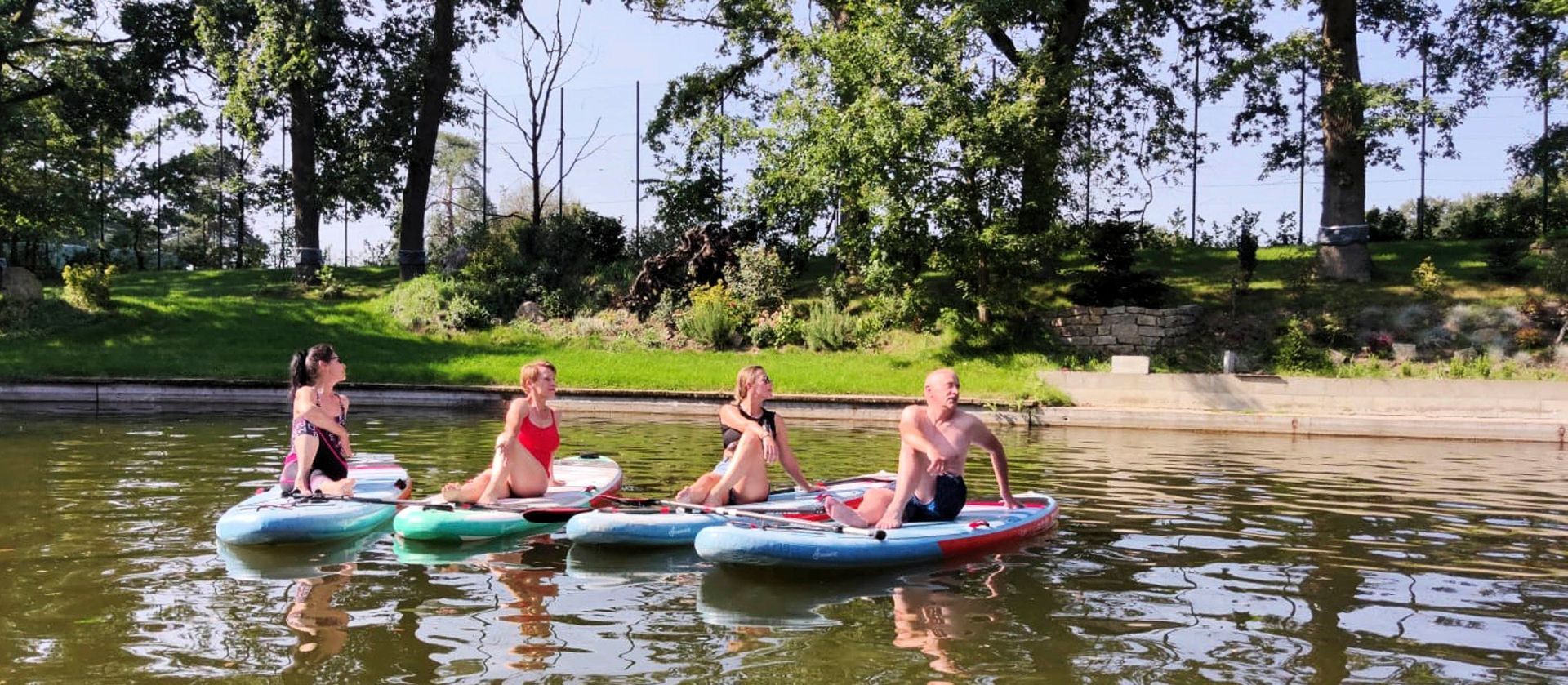 Eine Gruppe von Menschen sitzt auf Paddelbrettern im Wasser.