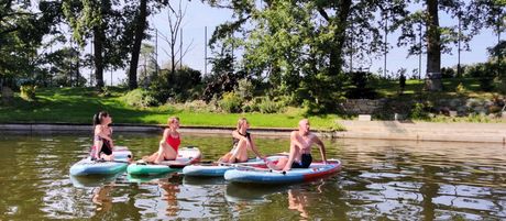 Eine Gruppe von Menschen sitzt auf Paddelbrettern im Wasser.
