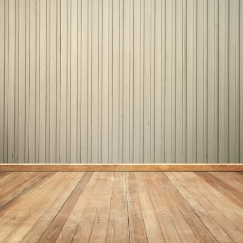Plancher en bois devant un mur lambrissé vertical beige clair.