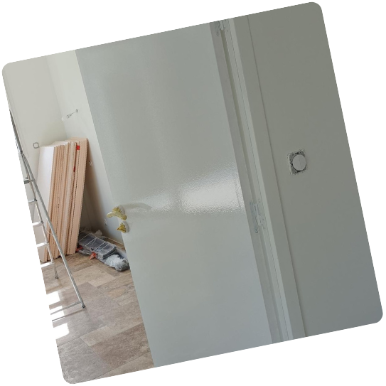 Porte intérieure en cours de peinture dans une pièce avec des matériaux de construction.