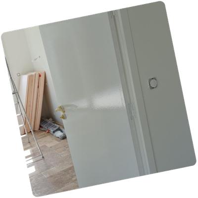 Porte intérieure en cours de peinture dans une pièce avec des matériaux de construction.