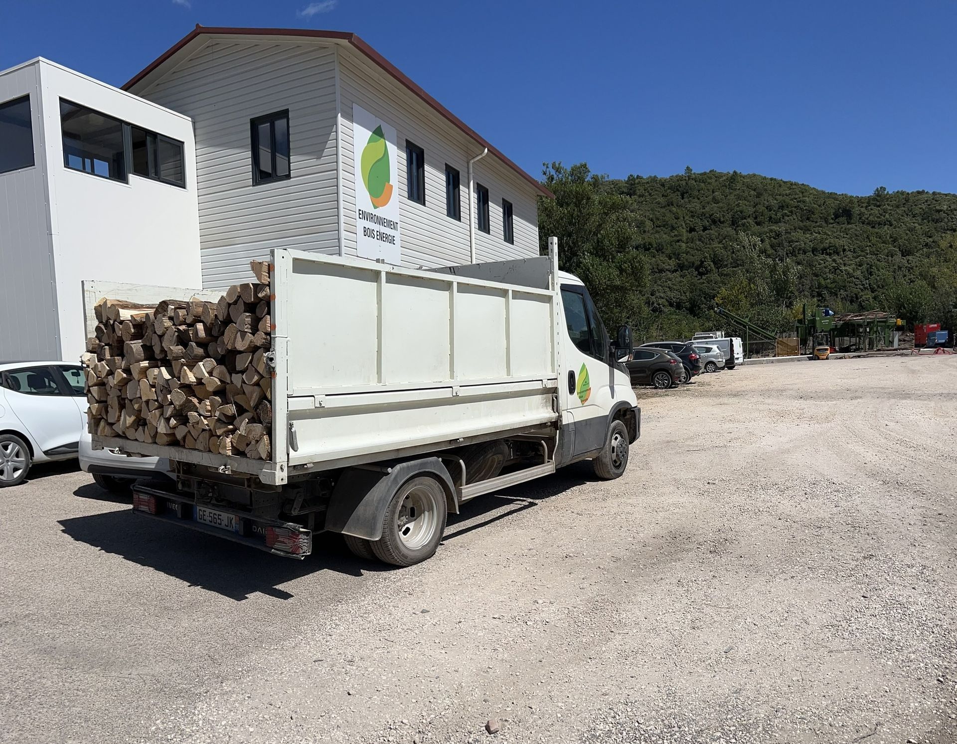 Camion benne avec des bûches de bois devant l'entreprise