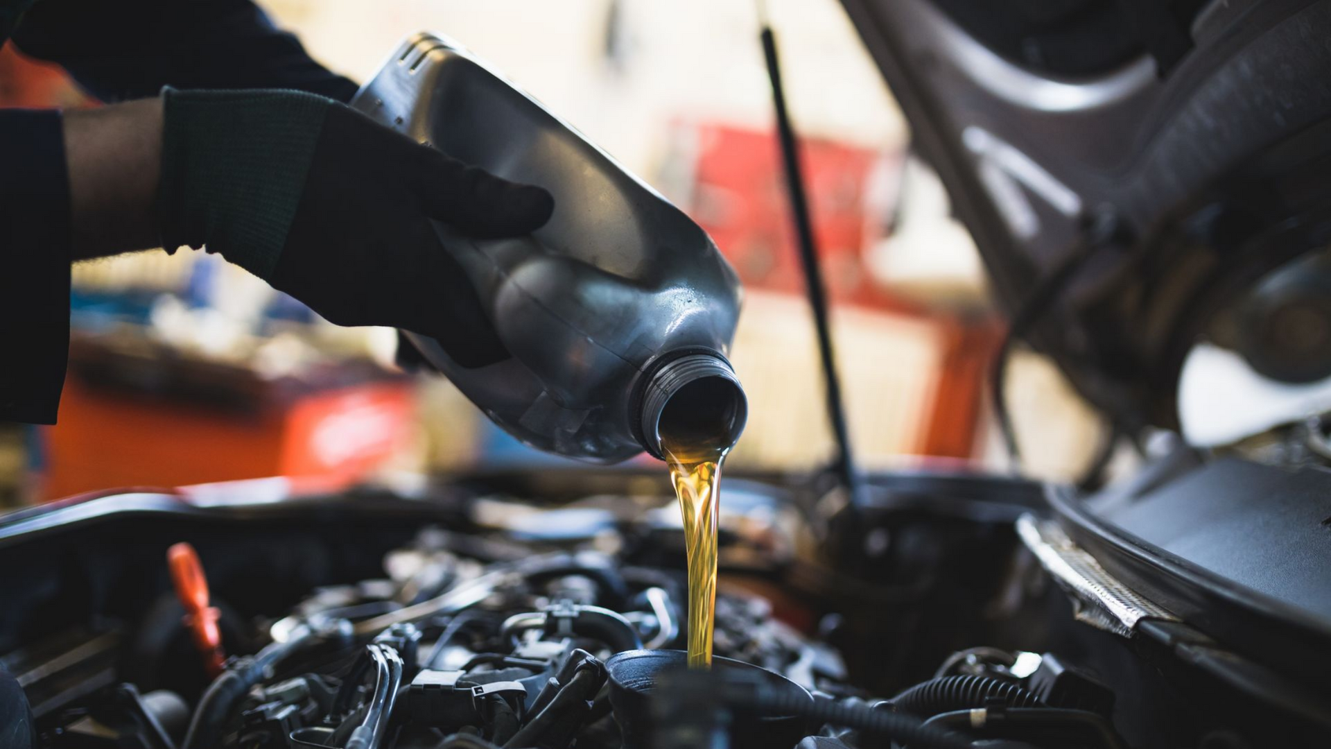 Un mécanicien verse de l'huile dans un moteur de voiture