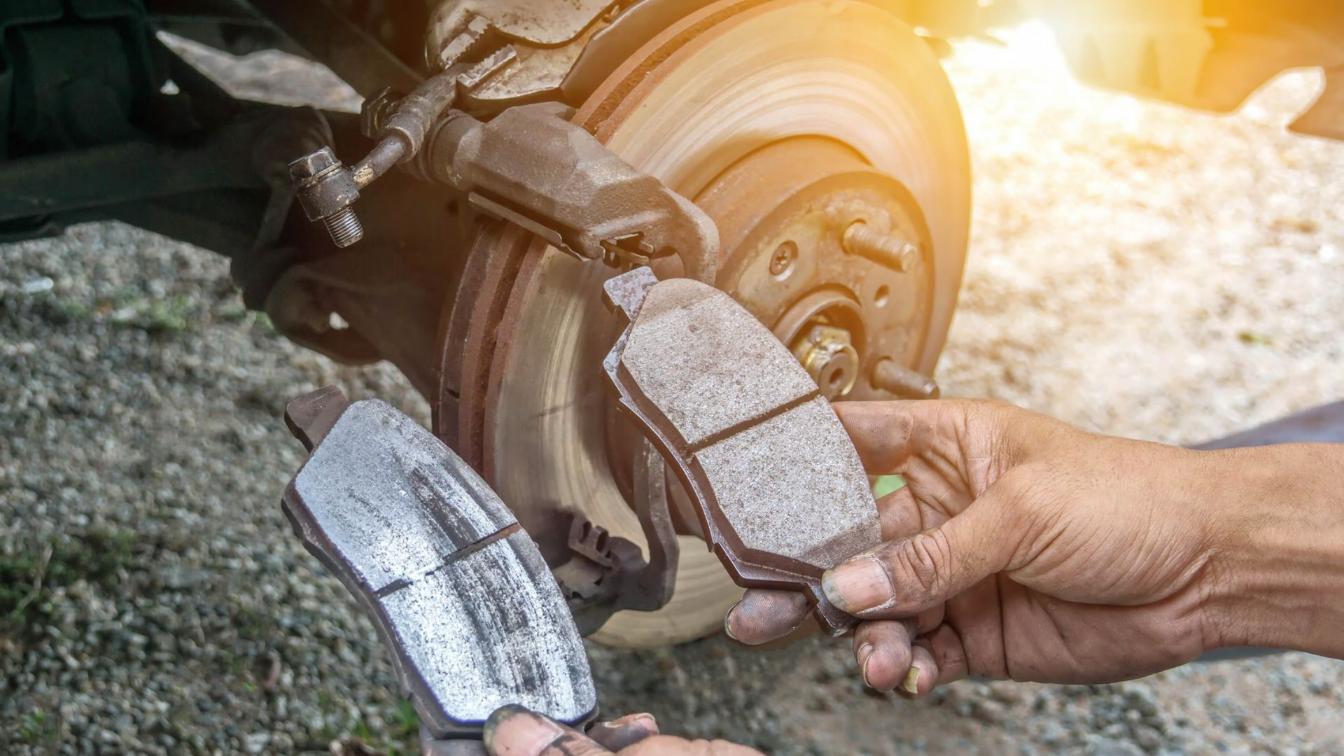 Le mécanicien tient 2 plaquettes de frein dont l'une est usée.