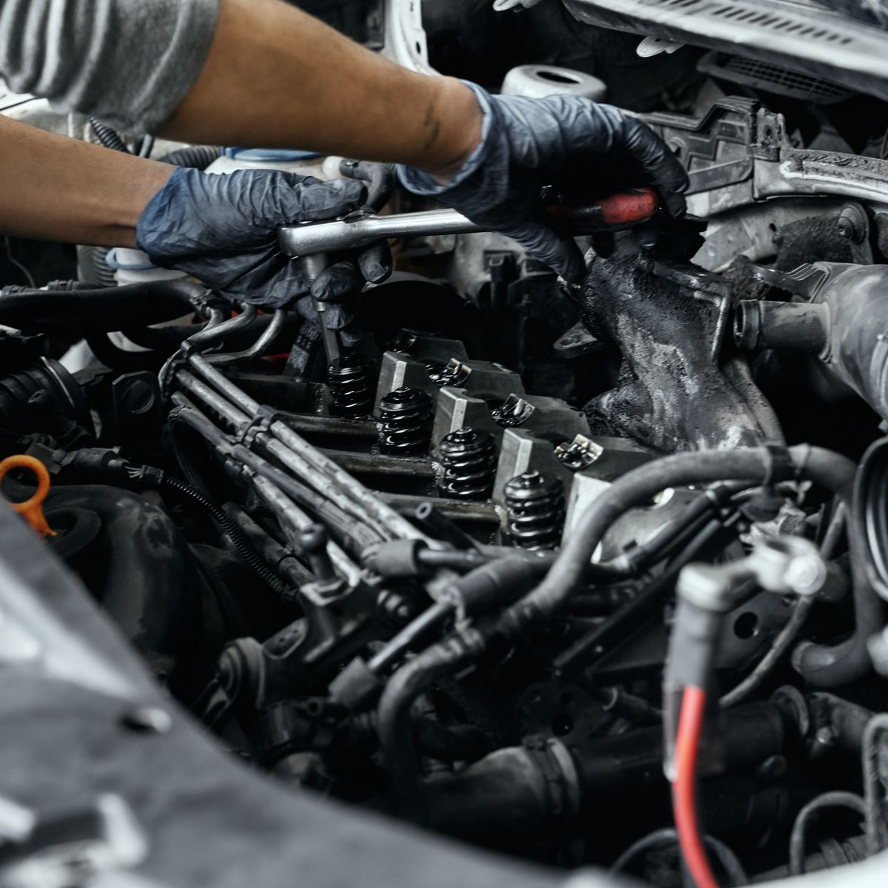 Un technicien a les mains dans un moteur de voiture.