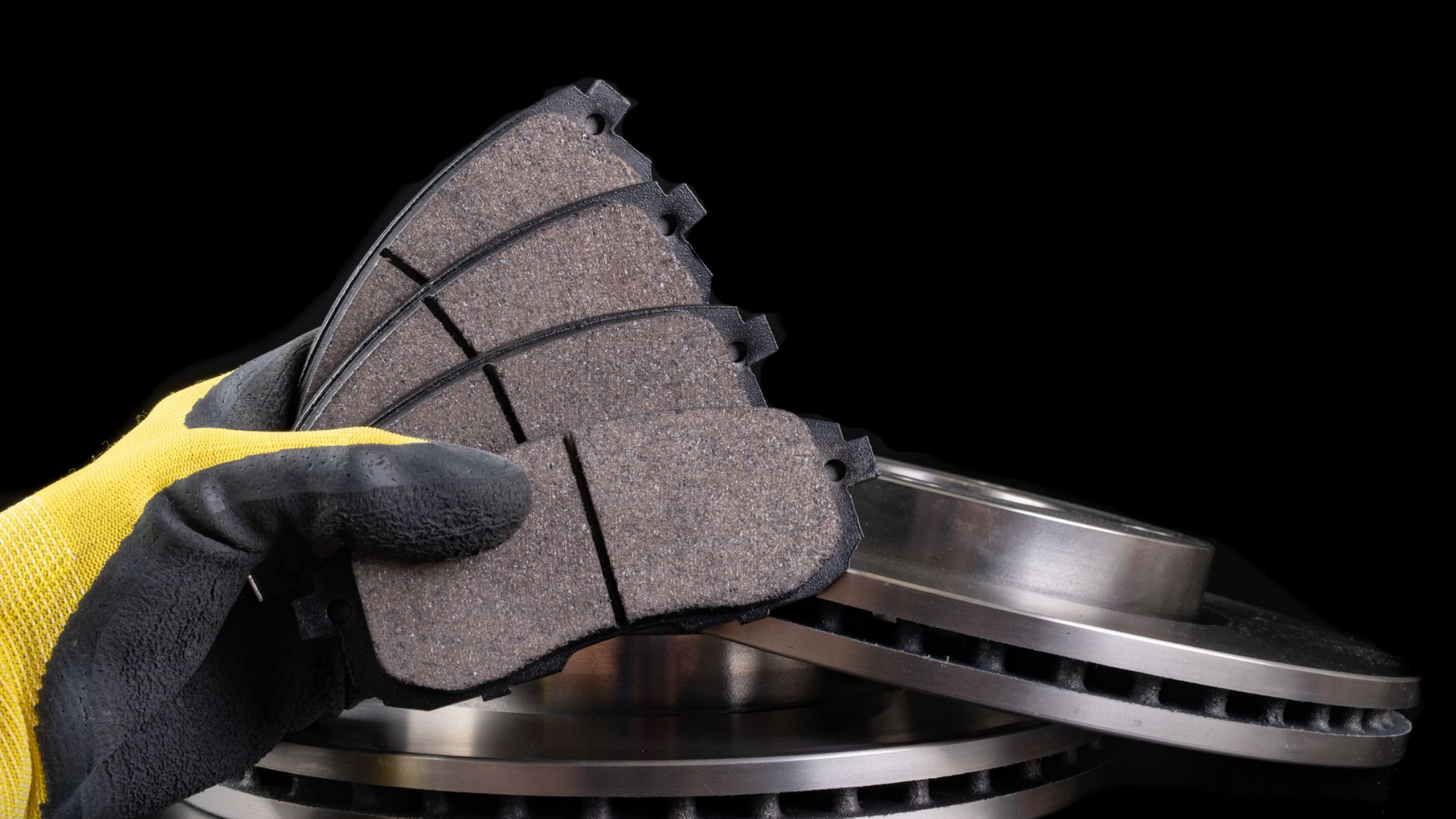 Une main avec un gant tient 4 plaquettes de frein.