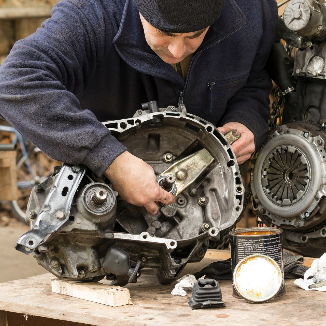 Le garagiste manipule une grande pièce détachée.